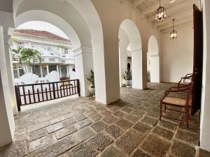 a hallway with arches and a porch with a chair at Arches Fort in Galle