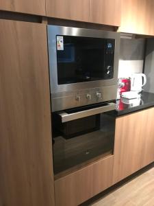 La cocina está equipada con horno negro y microondas. en Clínica Las Condes, espectacular departamento nuevo 80 m2 en Santiago