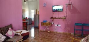 Homestay Langkawi Airport في كامبونغ بادانغ ماسير: غرفة معيشة مع جدران وردية وتلفزيون