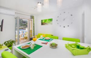 a dining room with a white table and green chairs at Apartments More in Sobra