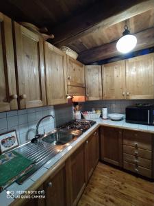 una cucina con armadi in legno, lavandino e piano cottura di Appartamento Lo Bou a Valsavarenche
