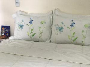 ein Bett mit zwei Kissen mit blauen Blumen darauf in der Unterkunft Aconchego próximo à Cascanéia e Blumenau in Gaspar