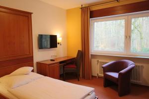 a bedroom with a bed and a desk and a window at Hardtwald Hotel in Bad Homburg vor der Höhe