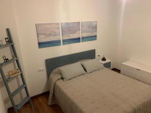 a bedroom with a bed with three paintings on the wall at Casa Mar y Sol in Corcubión