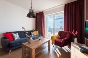 a living room with a blue couch and a red chair at P&O Apartments Służewiec in Warsaw