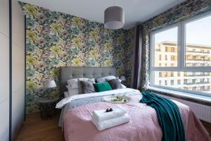 a bedroom with a pink bed with floral wallpaper at P&O Apartments Służewiec in Warsaw