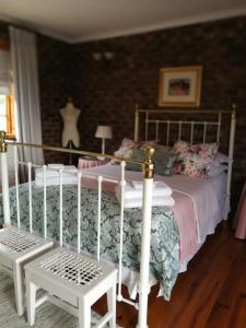 a bedroom with a bed with a white bed frame and a chair at Clarens Cottages in Clarens