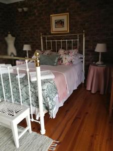 a bedroom with a white bed and a wooden floor at Clarens Cottages in Clarens