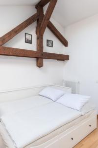 a bed in a white room with wooden beams at Comfy loft on Hlavna in Košice
