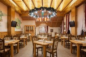 a restaurant with wooden tables and chairs and a chandelier at Ganz SKI Lift 5 in Bukovel