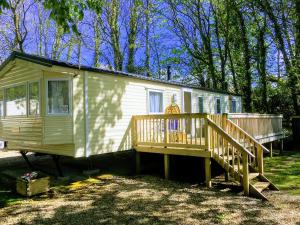 a yellow tiny house with a porch and a deck at Cornwall Caravan Holidays in Saint Minver
