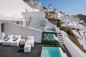 a balcony with white chairs and a swimming pool at Marizan Caves & Villas in Oia