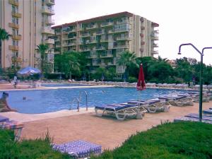 a large swimming pool with lounge chairs and a building at Sol y relax, AGUILA in Benalmádena