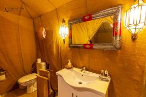 W łazience znajduje się umywalka, toaleta i lustro. w obiekcie Sahara Merzouga Luxury Camp w mieście Merzouga
