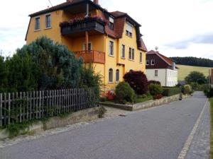 a yellow house with a balcony on a street at Ferienwohnung Familie Schneider in Neustadt in Sachsen