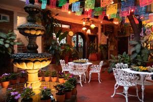 a restaurant with tables and chairs with flowers and a fountain at Hotel Posada De Roger in Puerto Vallarta