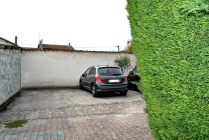 a car parked in a parking lot next to a hedge at Cocoon Appart 1 Miribel in Miribel