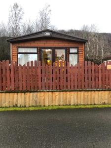 a wooden fence in front of a tiny house at 81 The Heathers, Aviemore Holiday Park , Dalfaber rd Aviemore PH22 1PX in Aviemore