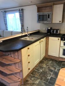 a kitchen with a sink and a microwave at 81 The Heathers, Aviemore Holiday Park , Dalfaber rd Aviemore PH22 1PX in Aviemore