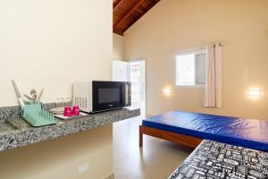um pequeno quarto com uma cama e uma televisão em Chales Agua Marinha em Ubatuba