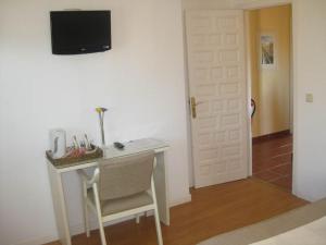 a white desk with a chair and a television on a wall at Hostal Tabanqueta in Cuenca
