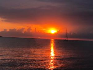 una puesta de sol sobre el océano con un velero en el agua en 5 Sterne Ferienhaus Charlotte, en Werdum