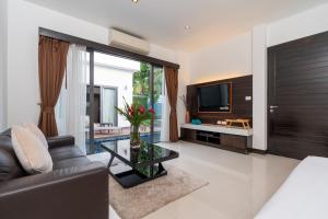 ein Wohnzimmer mit einem Sofa und einem TV in der Unterkunft The Harmony Pool Villa Phuket in Strand Bang Tao