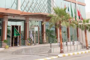 a building with palm trees in front of it at Brand Al Qassim Hotel in Buraydah