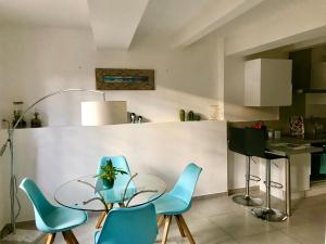 eine Küche mit einem Glastisch und blauen Stühlen in der Unterkunft La Maison du Courtil, Pistache-Chocolat in Moustiers-Sainte-Marie