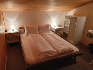 Bett in einem Zimmer mit 2 Tischen und einem Kühlschrank. in der Unterkunft Hotel Restaurant Bergheim in Flumserberg
