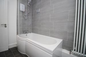 a bathroom with a white tub and a shower at Spacious 4BR Home Near Swansea Sleeps 8 in Swansea