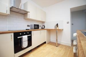 a kitchen with white cabinets and a black dishwasher at Spacious 4BR Home Near Swansea Sleeps 8 in Swansea