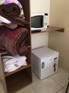 a small room with a microwave and a refrigerator at Pousada Acácia Amarela in Olímpia