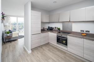 uma cozinha com armários brancos e um forno com placa de fogão em Vertex Luxury Suite em Croydon