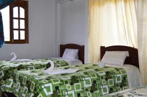 2 lits avec des cygnes dans une pièce dans l'établissement Quilotoa Green Lake, à Quilotoa