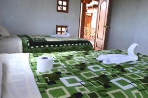- une chambre avec 2 lits et une serviette sur un lit dans l'établissement Quilotoa Green Lake, à Quilotoa