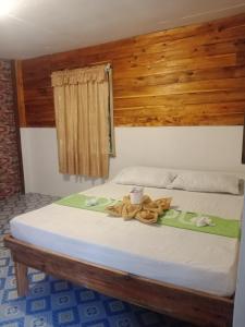 Una cama con cabecero de madera y toallas. en D' Angels Inn, Port Barton en San Vicente