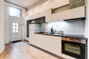 a kitchen with white cabinets and a black stove top oven at Diamond Residence - Marble Apartment in Budapest