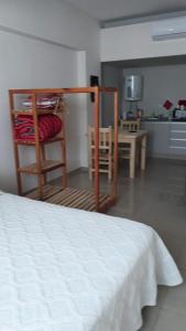 1 dormitorio con cama, mesa y cocina en relajado monoambiente en San Miguel de Tucumán