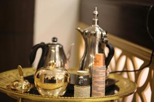 a gold tray with a tea kettle and stacks of plates at ريف قباء للشقق الفندقيه in Al Madinah