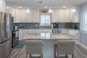 a kitchen with white cabinets and a large island with chairs at Waterfront & Pool Star5Vacations in St. Pete Beach