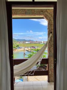 a window with a hammock looking out at a harbor at Casa Canal Barra da Lagoa in Florianópolis