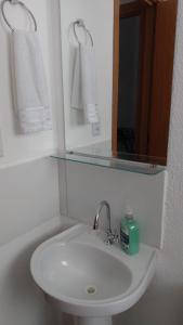 La salle de bains est pourvue d'un lavabo, d'un miroir et de serviettes. dans l'établissement Plaza Fraga Maia, à Feira de Santana