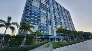 a tall building with palm trees in front of a street at Lumpini seaview cha-am By Greenview in Ban Sahakham