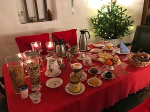 einen Tisch mit einem roten Tischtuch mit Essen und einem Weihnachtsbaum in der Unterkunft Haus am Markt in Königstein in der Oberpfalz
