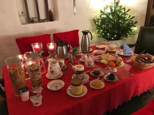 a table with a red table cloth with food and a christmas tree at Haus am Markt in Königstein in der Oberpfalz