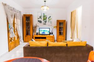 a living room with a brown couch and a tv at Villa A rabica - Extrait de Café in Pointe-Noire