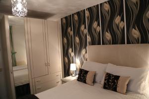 a bedroom with a bed and a wall with a flower pattern at La Suisse Serviced Apartments in Manchester