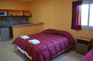 um quarto com uma cama com um cobertor roxo em Suyana Departamentos em Tinogasta