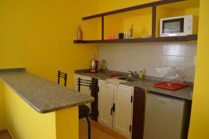 uma cozinha com paredes amarelas e um balcão em Suyana Departamentos em Tinogasta